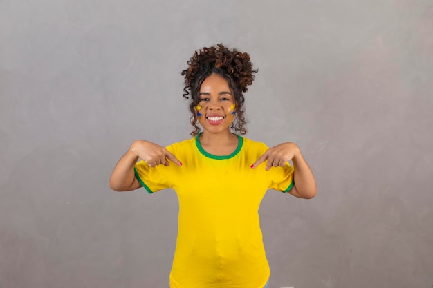 彼女の t シャツのテキストの空き領域を指しているブラジルの t シャツを持つ若いアフロ女性