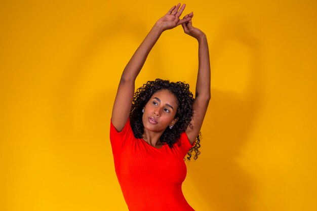 Young afro woman with curly hair smiling at camera on yellow background