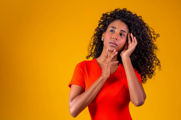 Young afro woman with curly hair smiling at camera on yellow background