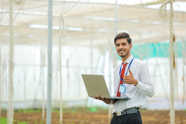 Young agronomist or banker with laptop at greenhouse