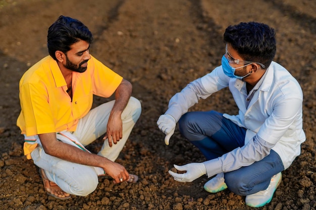 Young agronomist checking soil quality at field