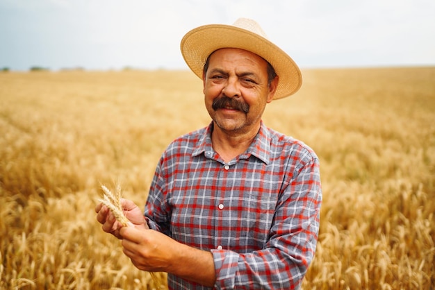 Young agronomist in grain field Farmer in the straw hat standing in a wheat field Cereal farming