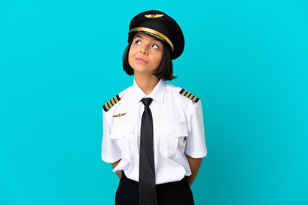 Young airplane pilot over isolated blue background and looking up