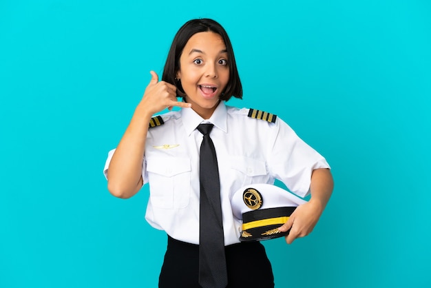 Young airplane pilot over isolated blue background making phone gesture and doubting