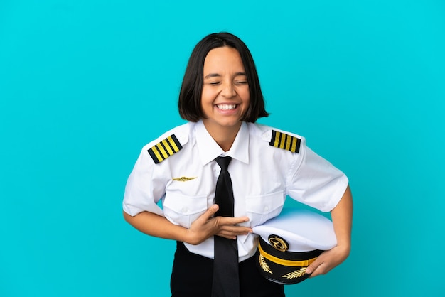 Young airplane pilot over isolated blue background smiling a lot