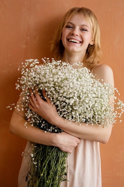 繊細な春の花の花束を持つ若い魅力的な女性