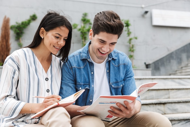 若い驚くべき愛情のあるカップルの学生の同僚は、本を読んでメモを勉強している外の屋外で。
