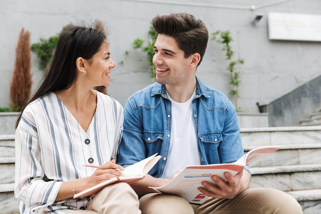 若い驚くべき愛情のあるカップルの学生の同僚は、本を読んでメモを勉強している外の屋外で。