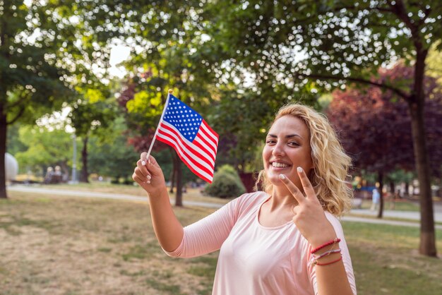 アメリカの旗を持っている若いすばらしい女性