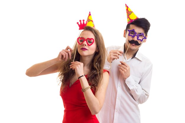 Young amazing woman  and young handsome man with celebrating hats holding card sticks of glasses