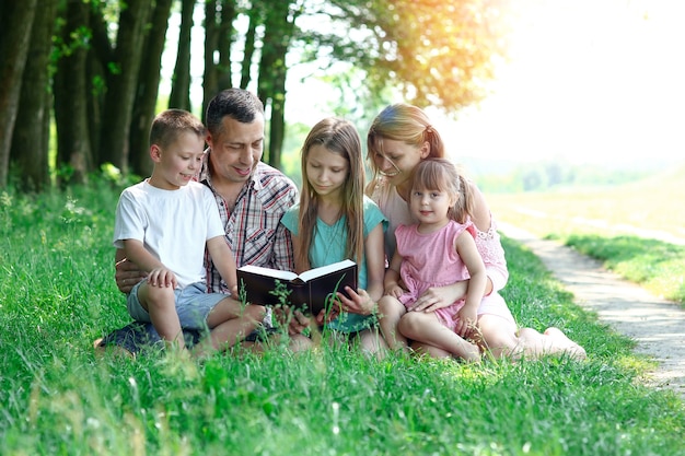 自然の中で聖書を読んでいる子供たちと若くて幸せな家族