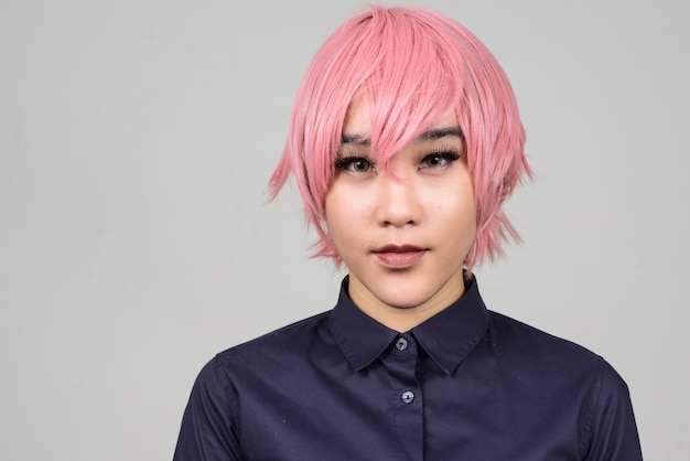 young androgynous Asian transgender woman against white wall