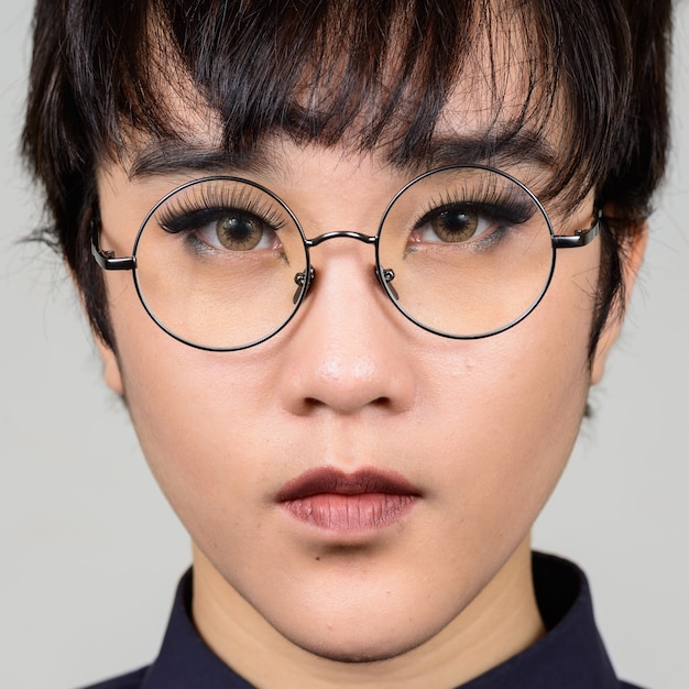 young androgynous Asian transgender woman against white wall