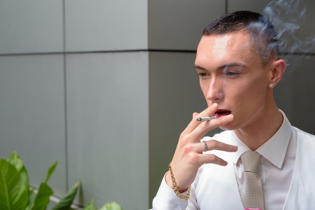 Young androgynous businessman smoking cigarette