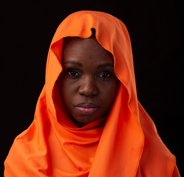 Young Angolan girl wearing dress and turban studio photo on a black background