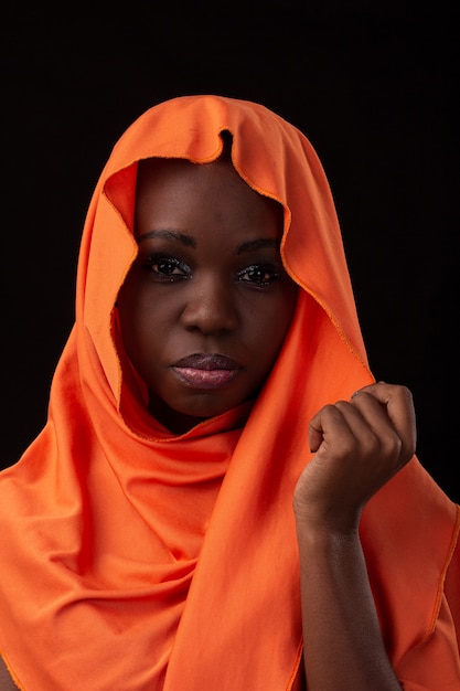 Young Angolan girl wearing dress and turban studio photo on a black background