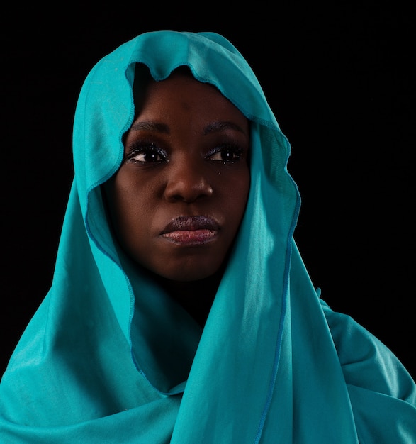 Young Angolan girl wearing dress and turban studio photo on a black background