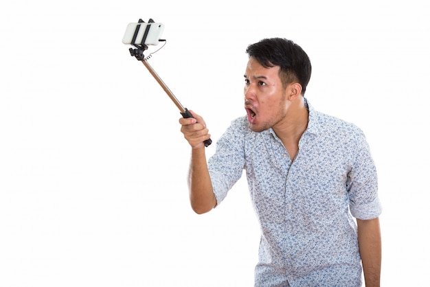 Young angry Asian man taking selfie picture with mobile phone