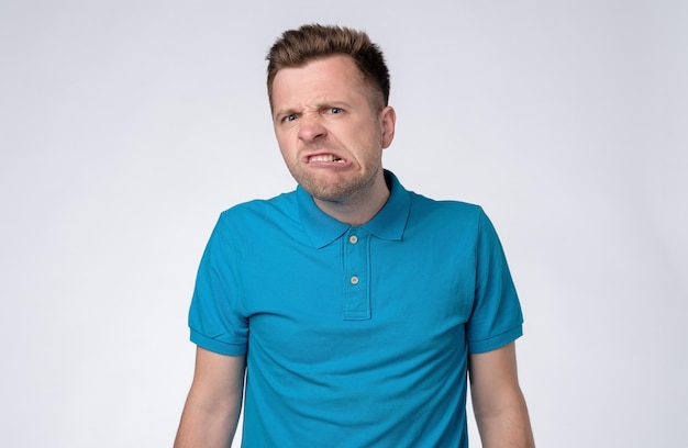 Photo young angry man is about to lose his temper on gray background