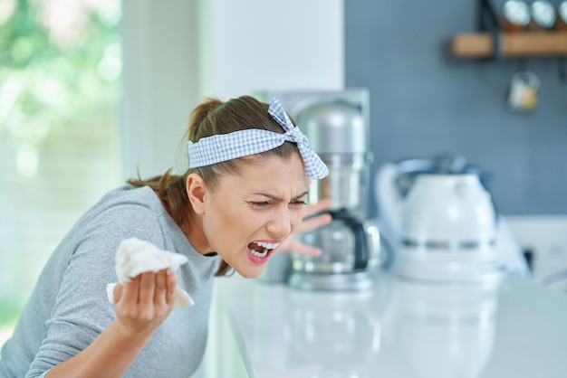 Young angry woman in the kitchen cleaning