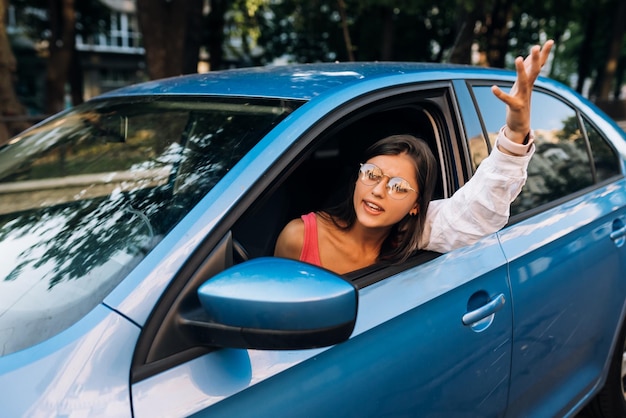 A young angry woman peeks out of the car window