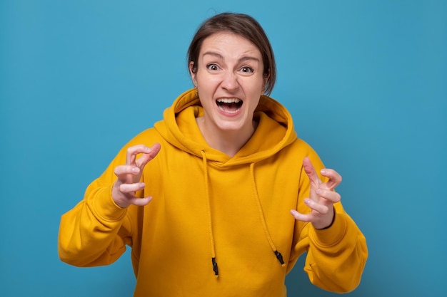 Young angry woman screaming clenching fingers. Studio shot