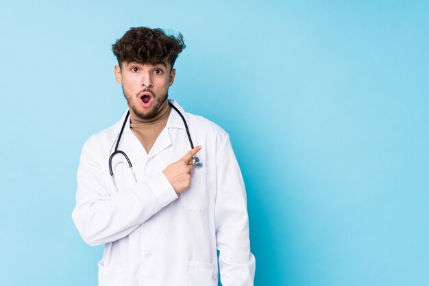 Young arab doctor man idolated pointing to the side