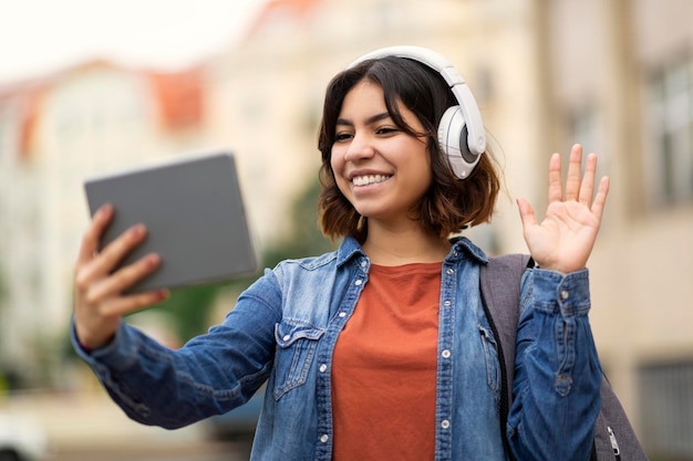 Young Arab Female Student Using Digital Tablet For Video Call Outdoors