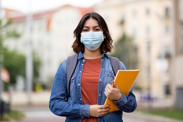 Giovane studentessa araba che indossa una maschera medica in posa all'aperto