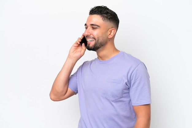 Молодой арабский красивый мужчина на белом фоне ведет разговор по мобильному телефону
