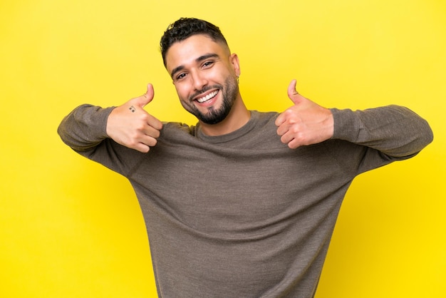 Young Arab handsome man isolated on yellow background giving a thumbs up gesture