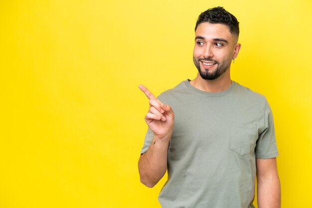 Young arab handsome man isolated on yellow background intending to realizes the solution while lifting a finger up