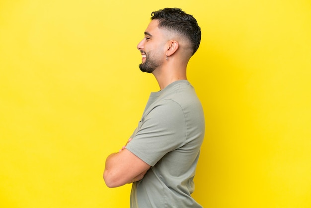Young Arab handsome man isolated on yellow background in lateral position