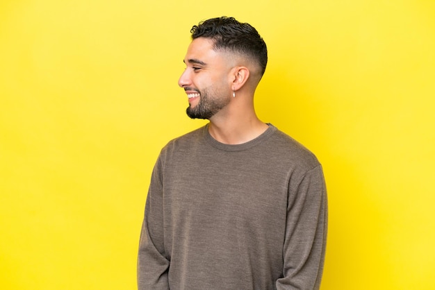 Young Arab handsome man isolated on yellow background looking side