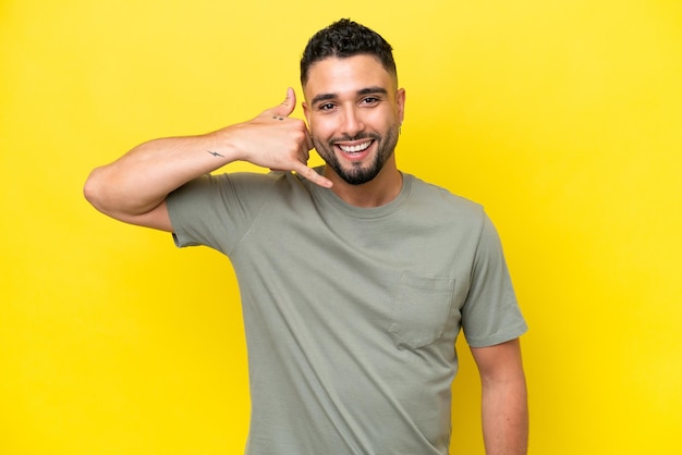 Young Arab handsome man isolated on yellow background making phone gesture Call me back sign