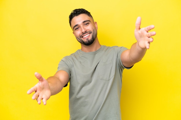 Young Arab handsome man isolated on yellow background presenting and inviting to come with hand