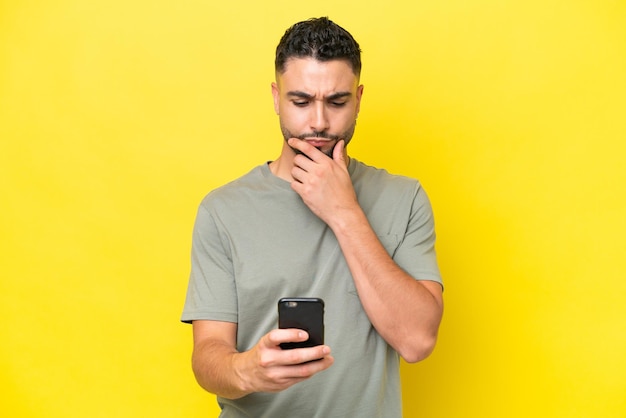 Foto giovane uomo bello arabo isolato su sfondo giallo pensando e inviando un messaggio