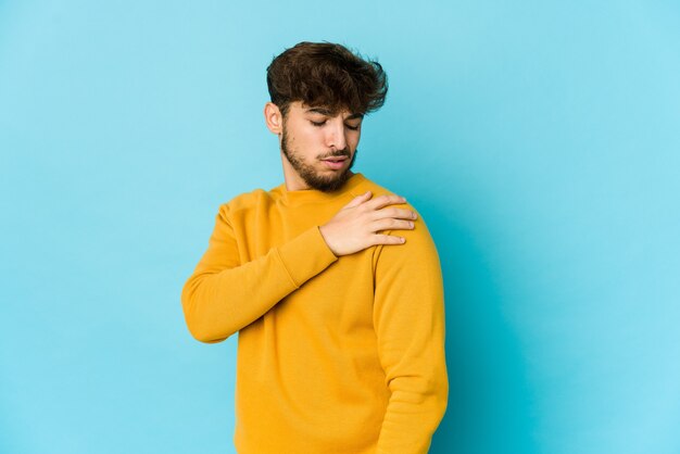 Young arab man on blue,  having a shoulder pain.