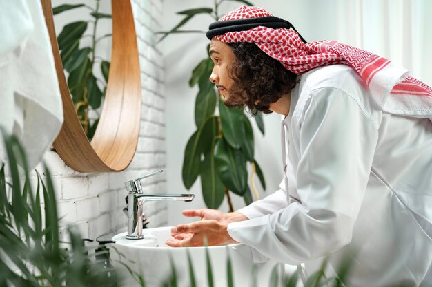 Foto giovane arabo che si prepara e guarda lo specchio in bagno