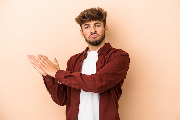 Young arab man isolated on beige background feeling energetic and comfortable, rubbing hands confident.