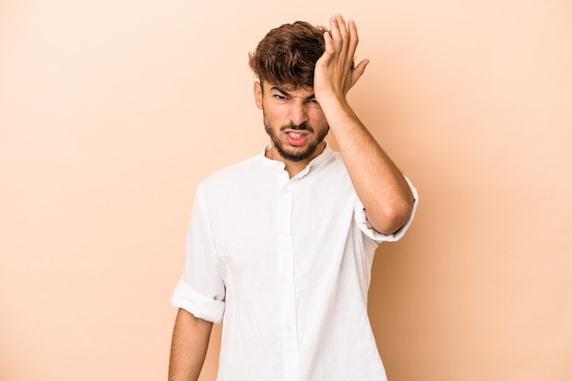 Young arab man isolated on beige background forgetting something, slapping forehead with palm and closing eyes.