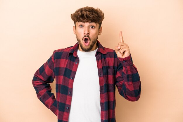 Young arab man isolated on beige background having an idea, inspiration concept.