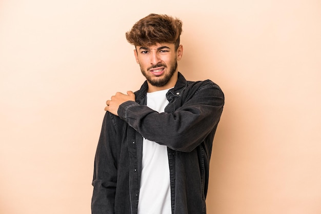 Young arab man isolated on beige background having a shoulder pain.