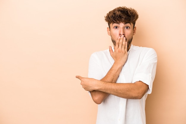 Young arab man isolated on beige background pointing to the side