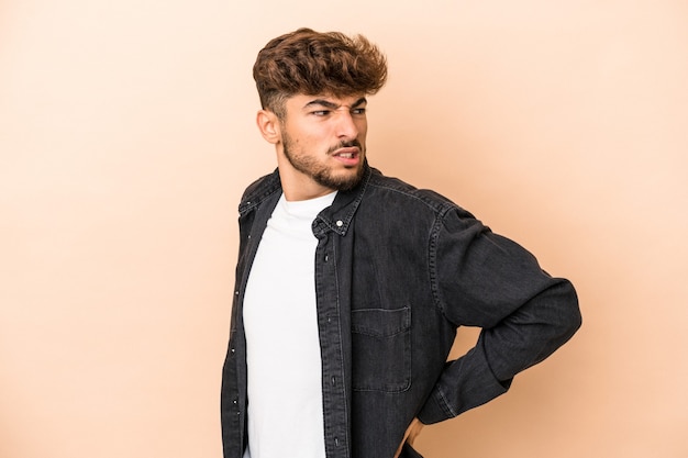 Young arab man isolated on beige background suffering a back pain.