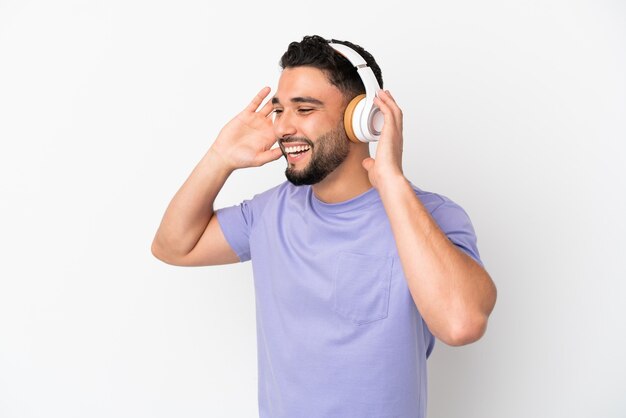 Young arab man isolated on white background listening music and singing