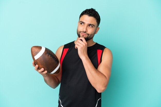 Photo young arab man playing rugby isolated on blue background and looking up