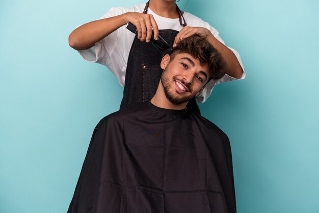 Giovane uomo arabo pronto a farsi tagliare i capelli isolato su sfondo blu