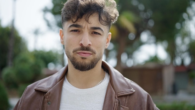 Young arab man standing with serious expression at park