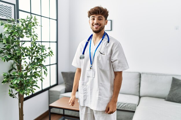 Young arab man wearing doctor uniform standing at clinic